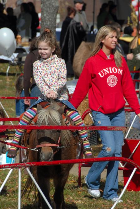 Janelle Musser (right) walks with a future Unionite during the pony rides at the Arts in the Park event during Homecoming. - Photo by Morris Abernathy