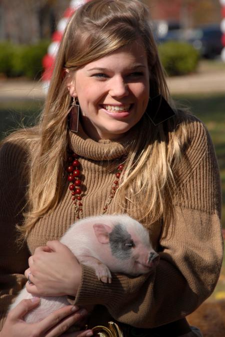 Freshman Molly Burns enjoys some time with a baby pig at the Arts in the Park event during Homecoming. - Photo by Morris Abernathy