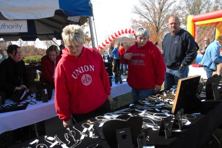 Alum and Union staffer Katrina Bradfield and her family look over the alum-made jewelry available at the Arts in the Park event during Homecoming. - Photo by Morris Abernathy
