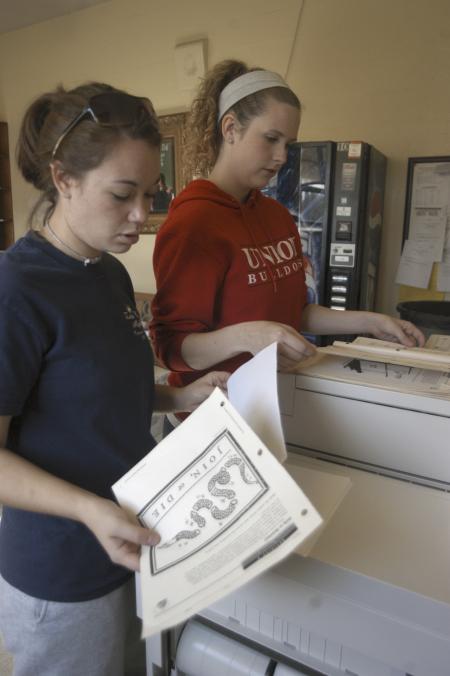 Junior Bekah McElhannon, Intercultural Studies major, and Junior Jessica Ramsay, family studies major, copy some papers to create a bulletin board for one of the teachers at Jackson Central-Merry High School during Day of Remembrance.  - Photo by Kyle Kurlick