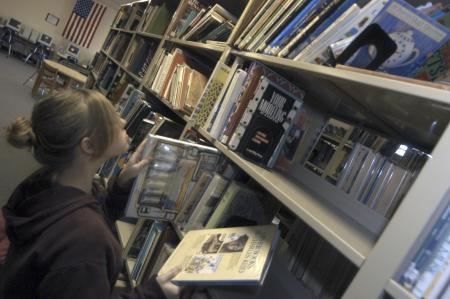 Freshman Pamela Penrose, psychology major, puts up some books in the library at Jackson Central-Merry High School during her Day of Remembrance project.    - Photo by Heather Phillips