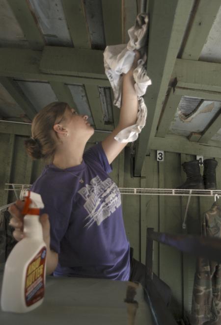 Sophomore Katie McHugh, education major, washes off the crossbeams in a barracks at Youth Town on Day of Remembrance. - Photo by Heather Phillips