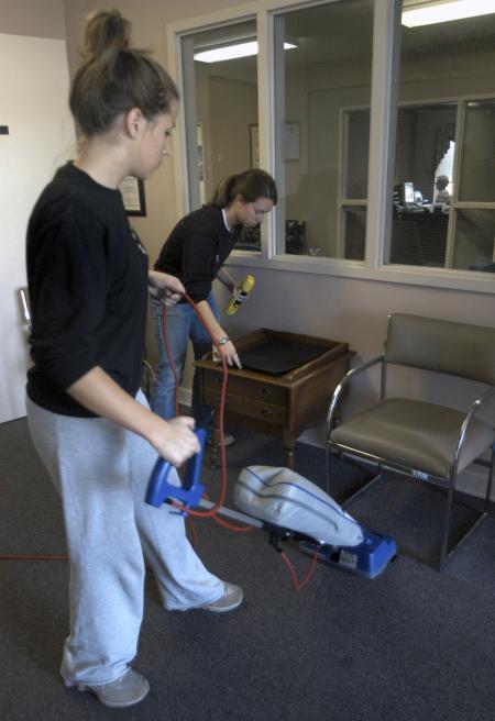 Freshman Brittaney Cole, undecided major, and Freshman Kristen Walker, nursing major, clean up the waiting room at Youth Town for a Day of Remembrance project.  - Photo by Heather Phillips