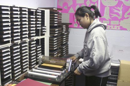 Freshman Lyda Kim uses an accu-cut board to make paper cut-outs of animals in order to decorate one of the classrooms at Iglesia Bautista Hispania Church located at Poplar Heights Baptist Church during Day of Remembrance. - Photo by Stephanie Schroeder