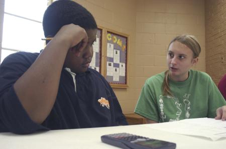 Freshman Heather Songer helps Damien with his homework at The Salvation Army after school during Day of Remembrance. - Photo by Stephanie Schroeder