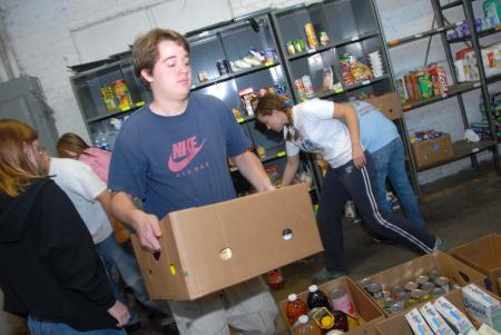 Jonathan Lambach helps move cans at RIFA during his Day of Remembrance project. - Photo by Morris Abernathy