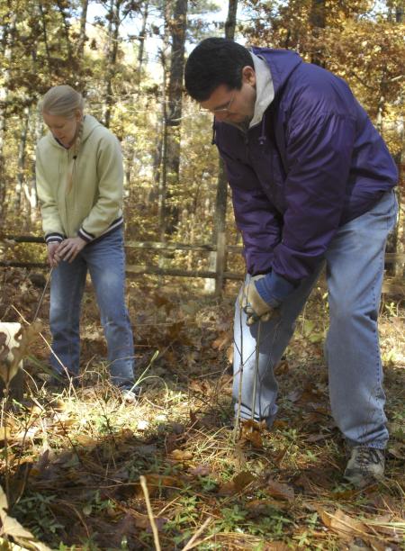 Keith Bates, assistant professor of history, and Junior Racheal Pressnell, history major, search the ground for buried gravestones with metal rods, at Ames Plantation during a Day of Remembrance project. - Photo by Matthew Diggs