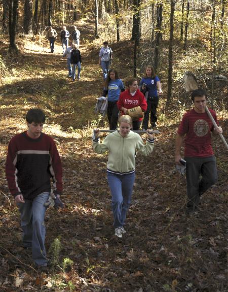Cameron Armstrong, Racheal Pressnell, Josh Abbotoy and the rest of the history department group walk out of the woods after searching for buried grave stones at the Ames Plantation during a Day of Remembrance project. - Photo by Matthew Diggs