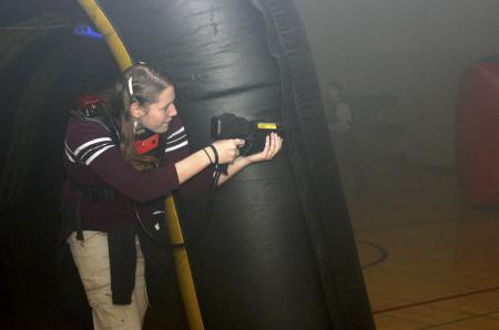 Nikki Fritts peers around a corner to tag people and gain points during the laser tag held in the small gym during Frost Fest put on by SAC. - Photo by Stephanie Schroeder