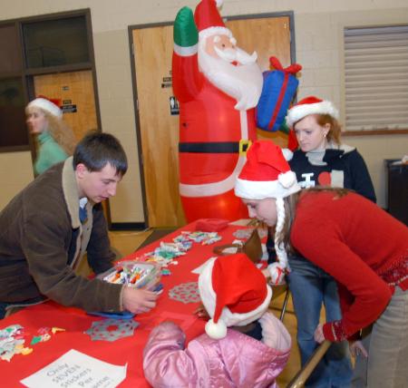 Cam Armstrong, Emily Watlington and Kinsey Bolinger color with one of the children during the SAC Carl Perkins' Christmas Party. - Photo by Morris Abernathy