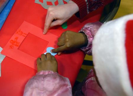 Emily Watlington helps a child with a crafts project during the SAC Carl Perkins' Christmas Party. - Photo by Morris Abernathy