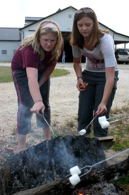 Rising Seniors Victoria Allen and Jessica Pikowski roast marshmallows and make s'mores during a cookout at the home of the Abshers. - Photo by Stephanie Schroeder