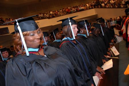 Education graduates spend time in prayer at the start of the August graduation ceremony. - Photo by Morris Abernathy