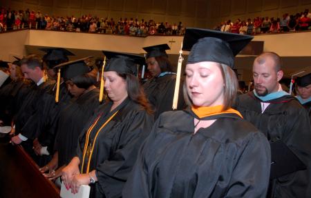 Business and nursing graduates spend time in prayer at the start of the August graduation ceremony. - Photo by Morris Abernathy
