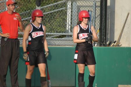 Amy Chatham (left) and Michelle Albonetti (right) watch the pitcher prior to their at bat.  Assistant Coach Steven Gream watches as well. - Photo by Steven Aldridge