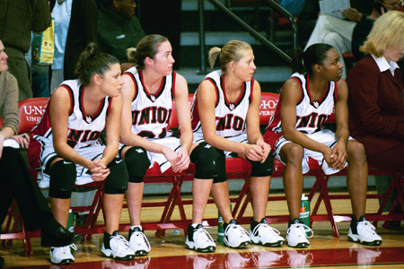 Freshman Jennifer Henson (11), Freshman Peggy McCain(21), Sophomore Laura Davison (15), and Sophomore Monica Elliot (24) look on from the bench. - Photo by Jim Veneman