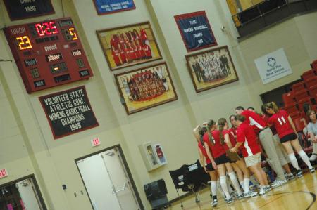 Coach Steven Gream talks with the Lady Bulldogs during a time-out, while the score board on the wall displays who is winning.  - Photo by Neisha Fuson