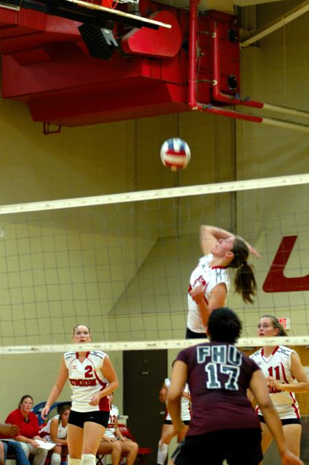 Junior Tiven Catrett goes up for the spike in a Union match versus Freed-Hardeman.  Union's CJ Neathamer (2) and Jennifer Martins (11) look on. - Photo by Matt Elia