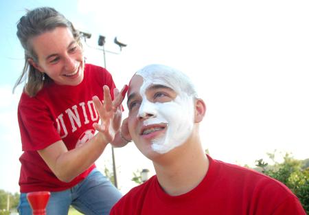 Junior Kasey Cobb, sociology & family studies major, helps Junior Jonathan Lambach get ready to cheer on the Soccer teams. - Photo by Matthew Diggs