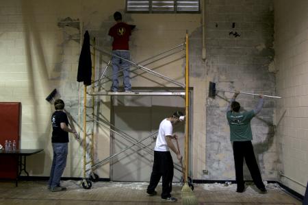 Members of SAE fraternity: (from left) Scott Goff, Jeff Norris, Casey Kidd and Luke Burleson work on stripping paint off one of the gym walls at the Augustine school to prepare for a fresh coat of paint during Day of Remembrance. - Photo by Kyle Kurlick