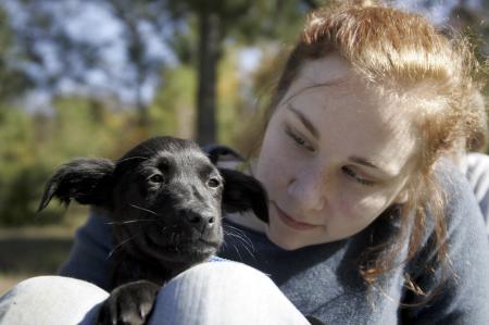 Lori Landon, along with the other girls who served Day of Remembrance at the Jackson Madison County Humane Society, plays with puppies in the front yard. All the girls wished they could bring one to live with them in their dorms. - Photo by Kyle Kurlick