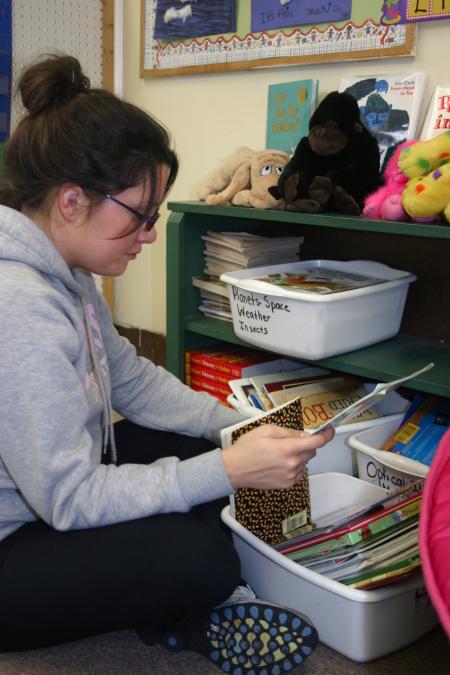 Freshman Jessica Hall sorts through and organizes books for a teacher at Whitehall Elementary School during Day of Remembrance. - Photo by Stephanie Schroeder
