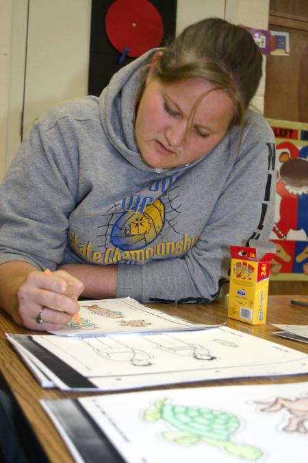 Freshman Kasey Wilkinson colors pictures for a teacher's lesson at Whitehall Elementary School during Day of Remembrance. - Photo by Stephanie Schroeder
