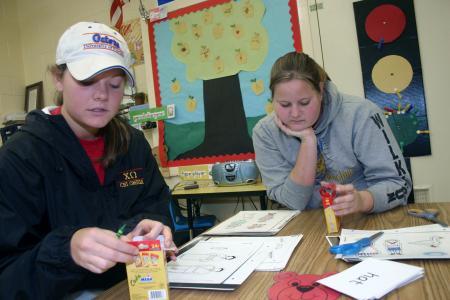 Sophomore Katherine Carr and Freshman Kasey Wilkinson color pictures for a teacher's lesson at Whitehall Elementary School during Day of Remembrance. - Photo by Stephanie Schroeder