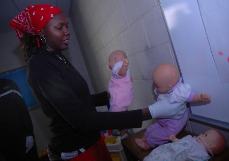 During Day of Remembrance, Junior Josephine Owino cleans the baby dolls that J-Crib Ministries has for children that come in to their classrooms.  - Photo by Neisha Fuson