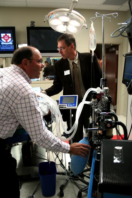 Mark Kossick demonstrates the technology in the simulation labs and lets alums test it out during the School of Nursing's homecoming reception. - Photo by Kristi McMurry Woody