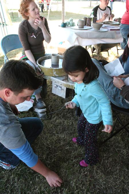 Alum Brian Bain and his daughter Elinor enjoyed watching Lily Zophi, junior art major, throw pots during Homecoming's Arts in the Park. - Photo by Kristi McMurry Woody