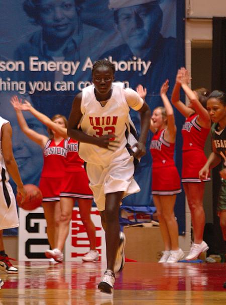 Freshman Zeinab Chan runs back down the court during the NAIA while the cheerleader's yell in the background.  - Photo by Neisha Fuson