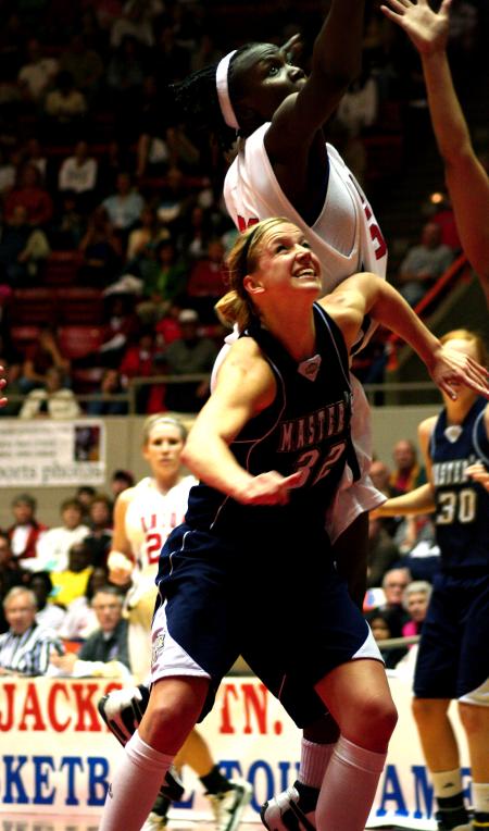 Josephine Owino jumps high over the heads of her opponents, The Master's, to get a rebound during the second game of the NAIA tournament. - Photo by Kristi McMurry Woody
