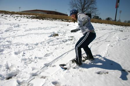 Snow covered Union's campus the night of Mar. 7, and students took a break from studying to play in it. Sophomore Leah Heinsch tries to snowboard by the soccer fields. - Photo by Stephanie Schroeder