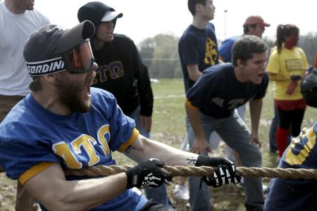 Andrew Corbett shouts to boost his strength as he and members of ATO work to win the tug-of-war competition at the Greek Olympics as fellow fraternity brothers cheer for their team. - Photo by Kyle Kurlick