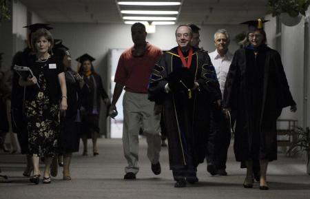 President Dockery (center) walks down the hallway to the Fred DeLay Gymnasium with Provost Carla Sanderson (right) to preside over the summer graduation ceremony. - Photo by Justin Veneman