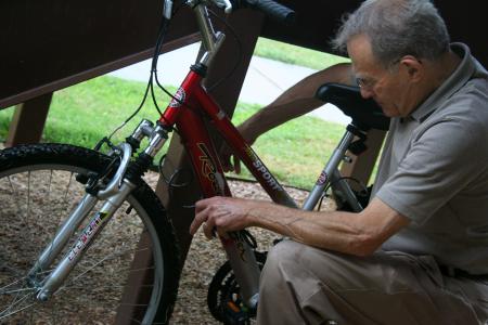 Ed Huthman, grandfather of Emily Huthman, patiently figures out his granddaughter's bicycle lock during move-in day for new students.  Huthman says he has moved several children and grandchildren into college, but &ldquo;this is the first time people have been standing around to help.&rdquo; - Photo by Kristi McMurry Woody