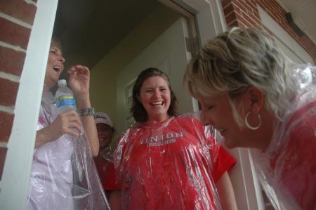 Union staffers Stephanie Kesner, Belinda Moss and Kartina Bradfield laugh as they try to put their muddy shoes on during Freshmen move-in day. 
 - Photo by Beth Spain