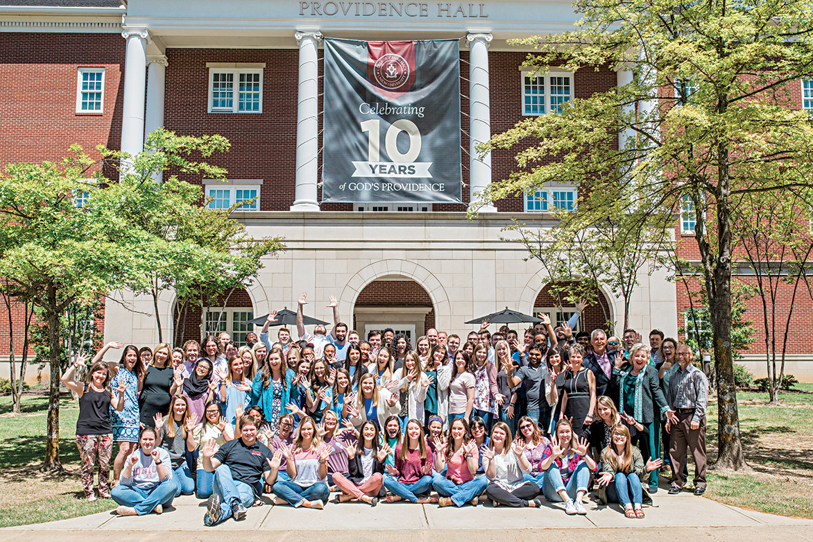 The College of Pharmacy poses in front of their 10-year anniversary banner