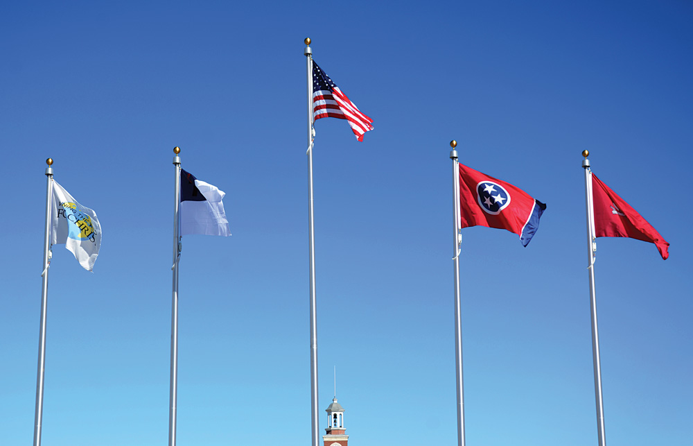 Flags donated by the 1963 Graduating Class are raised for the first time at the campus entrance during Homecoming.