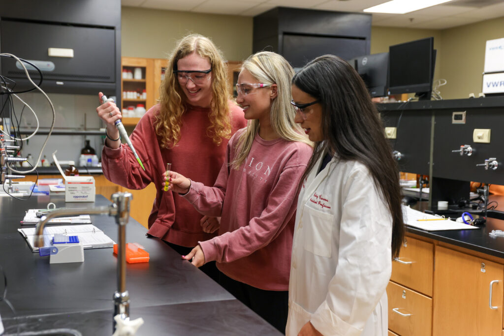 Betsy Caceres working with students in chemistry lab