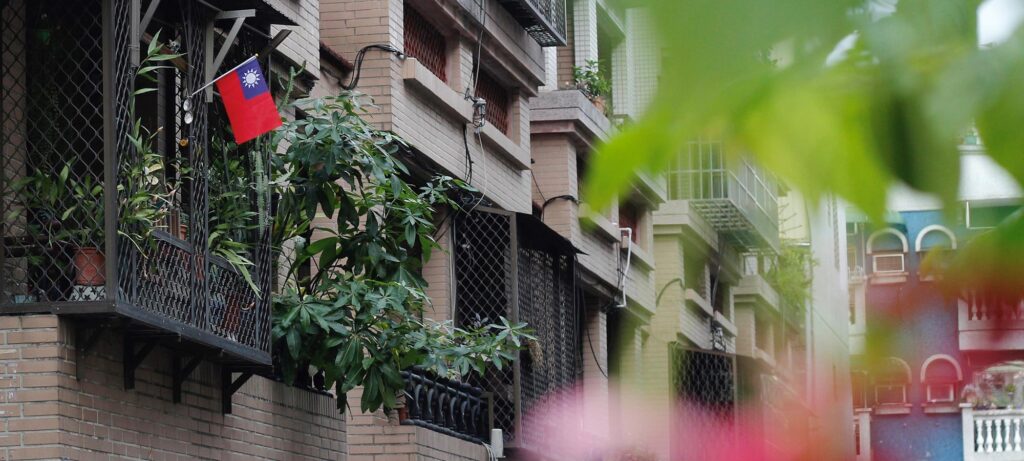 A Taiwan flag hangs from the balcony of a brick residential building, surrounded by greenery, with other apartment balconies in view—reflecting the global presence of Union University graduates making an impact for Christ.