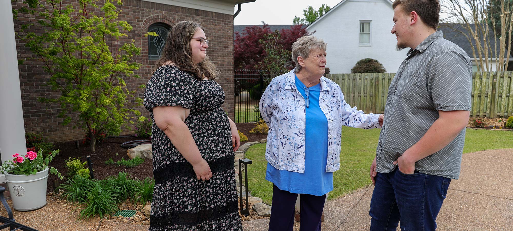 Rhonda Wallace, a Union donor known for her scholarship support, stands outside with two others near a house—the woman in a floral dress on the left and an older woman in blue at the center.