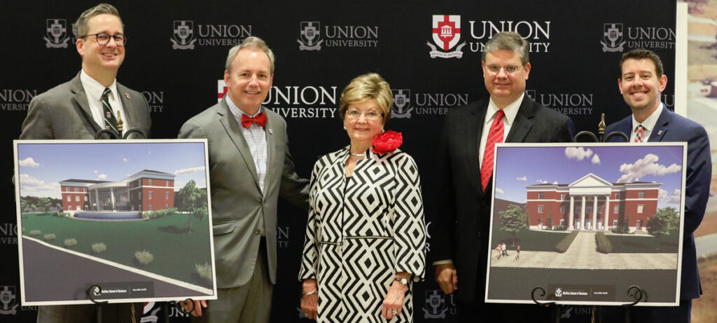 Five people stand in front of a Union University backdrop, posing with two architectural renderings of new academic buildings set to overlook the Great Lawn. The group is dressed in business or formal attire.