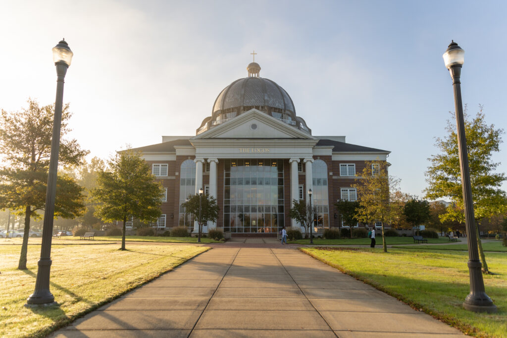 A large brick building with a glass entrance and a domed roof, flanked by lamp posts and trees, is shown on a sunny day. The building has THE UNION above the entrance—Union's main campus is in Jackson, Tennessee.