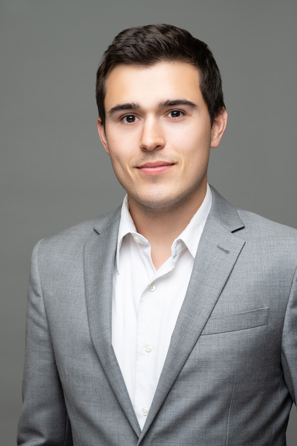 Michael Cochran, a man in a grey suit jacket and white dress shirt looking at the camera.